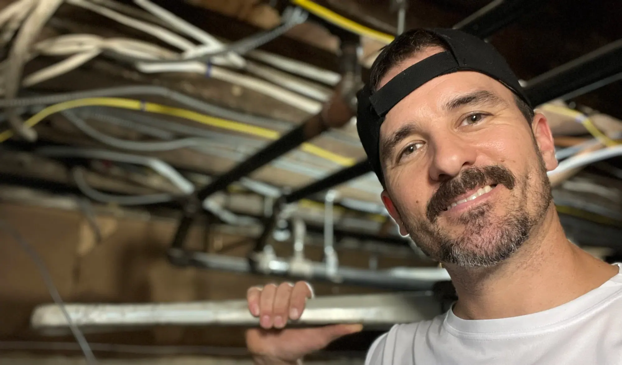 Frank Karichko working beneath exposed plumbing lines