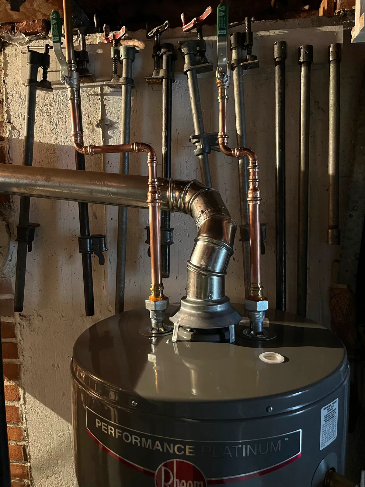 Copper piping, shutoff valves, and a metal vent above a tank water heater